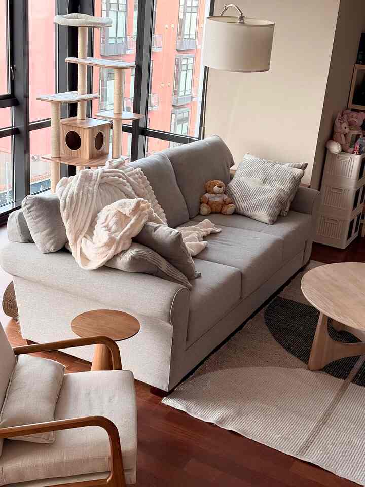 Beige and wood-toned living room featuring gray sofa and large cat tower, creating a warm and cozy atmosphere