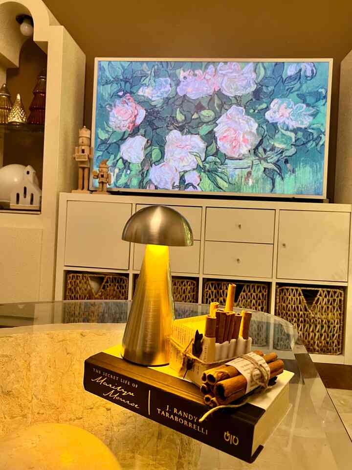 Cozy living room with warm lights and cinnamon candles, featuring white shelves and a mid-century modern lamp creating inviting atmosphere