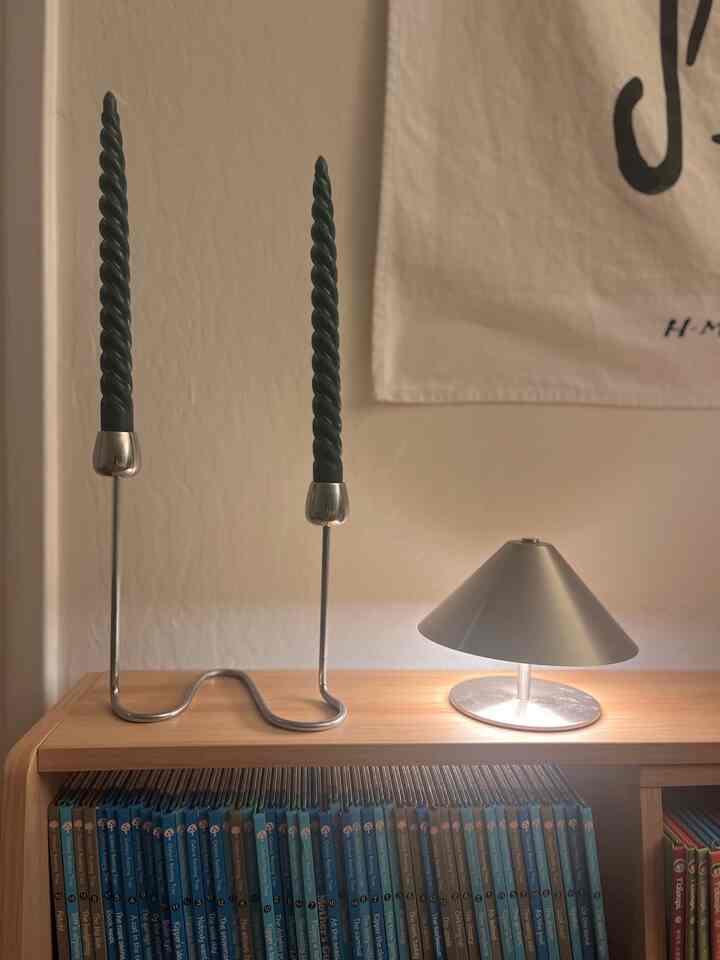 Cozy interior with silver candlesticks and a silver table lamp placed on a wood-tone shelf