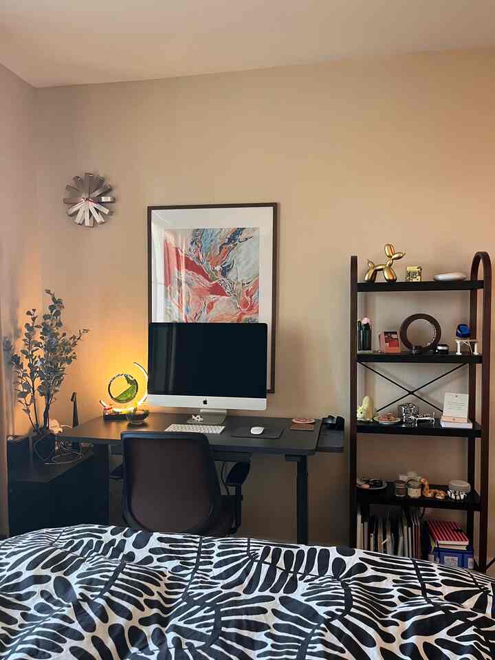 Beige-toned bedroom home office featuring modern desk and chair with multi-purpose shelving for a cozy workspace