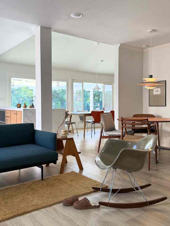 Natural toned living and dining room featuring a blue sofa, wooden furniture, rug, and pendant lights with clean modern aesthetic