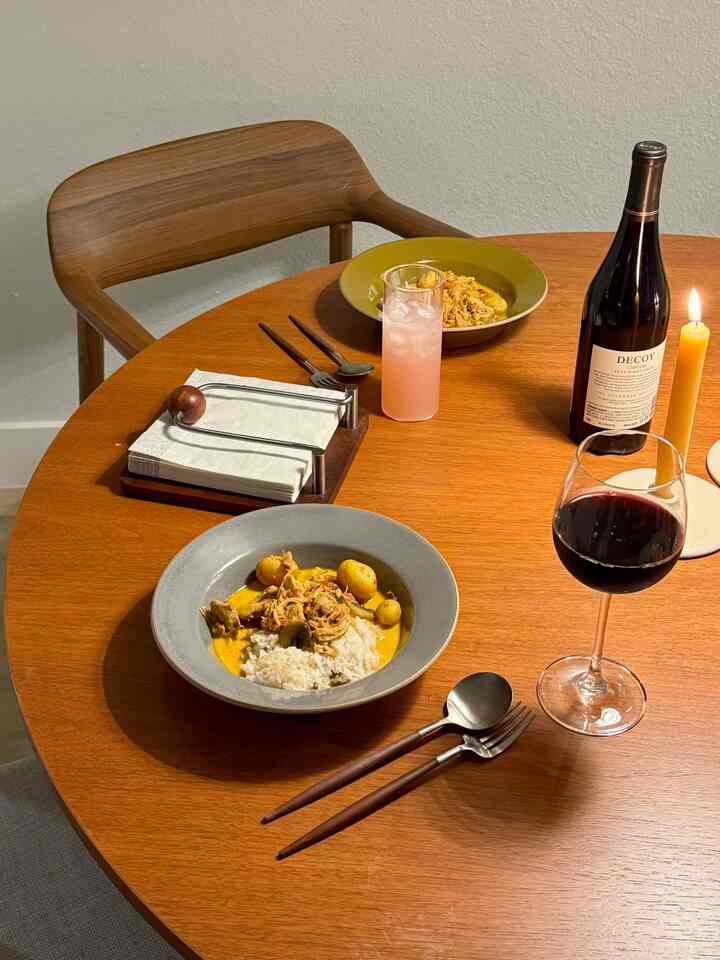 Cozy dining room with warm wood-toned table and candlelight, featuring food and wine creating a relaxed atmosphere