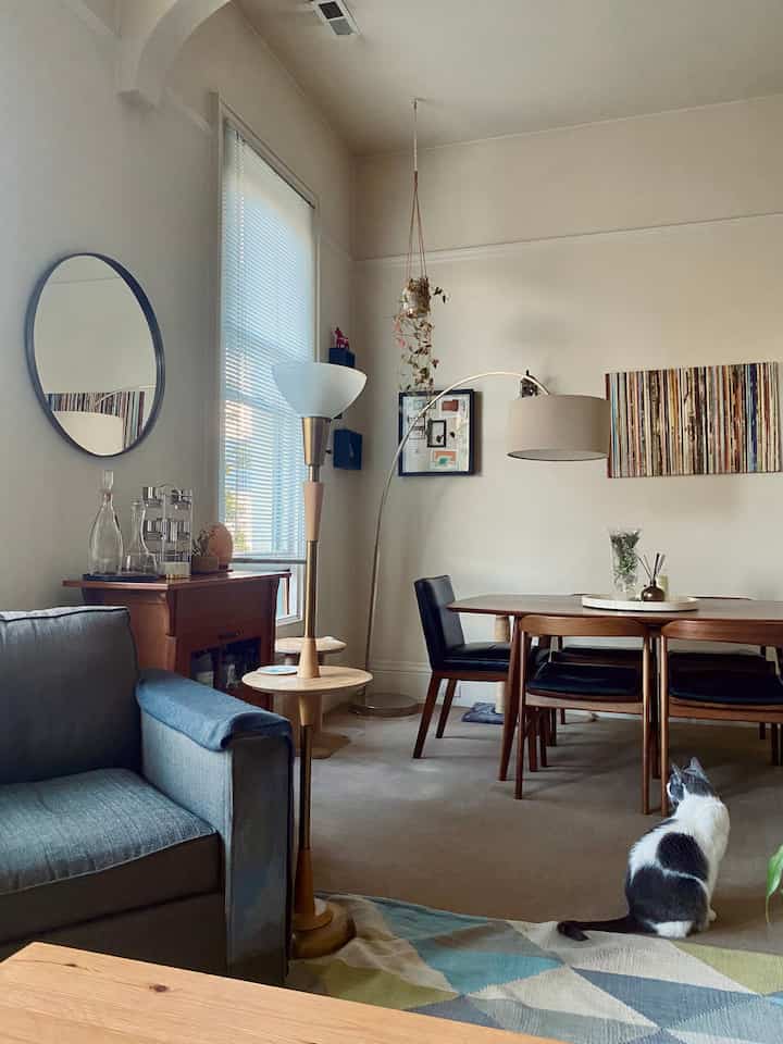 Natural-toned living and dining room featuring mid-century modern furniture and a cat with cozy atmosphere
