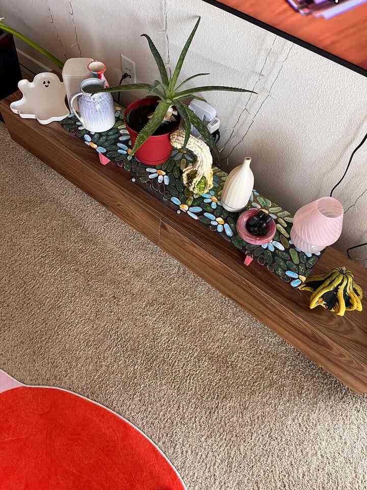 Brown wood-toned living room featuring a monitor stand with plants and decorative elements in a cozy setup