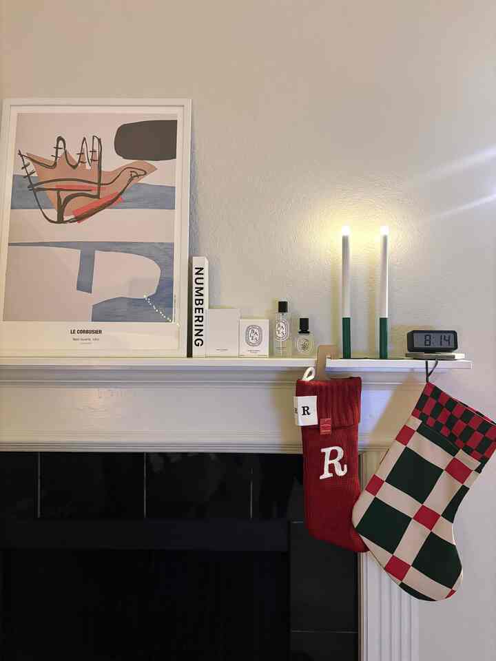 White-walled living room featuring fireplace mantle with Christmas stockings and lit candles creating cozy festive atmosphere
