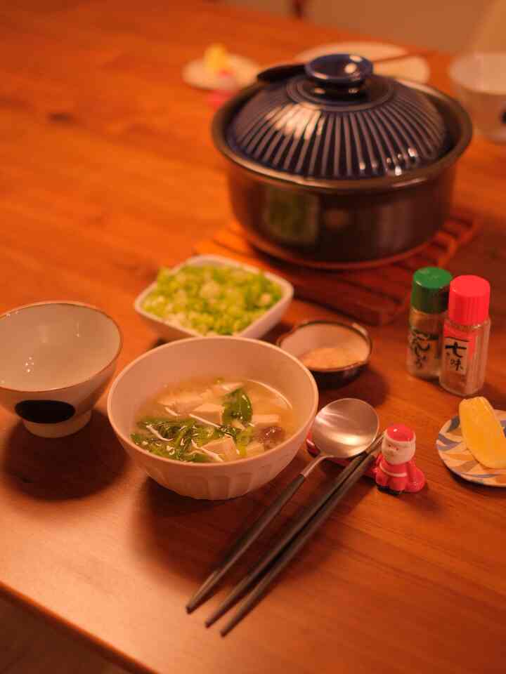 Cozy dining setting with warm orange lighting, wooden table featuring Santa cutlery rest and Japanese tableware