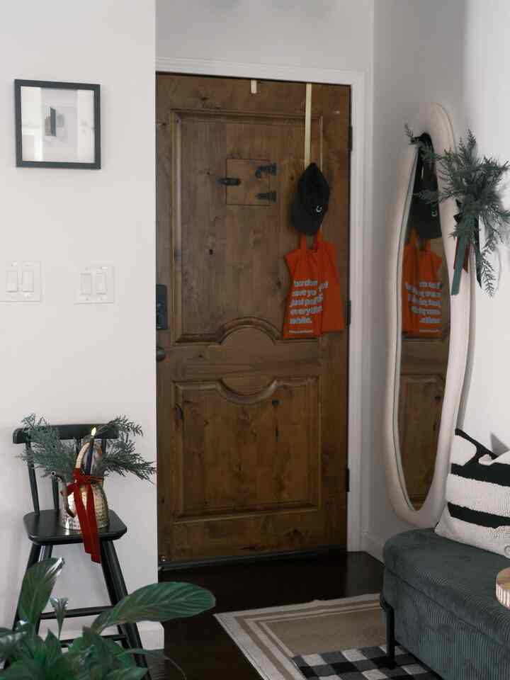 Wood tone entrance space featuring a large full-length mirror and a sofa with cushions, creating a cozy atmosphere