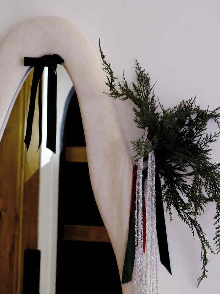 Small, simple entrance with cream-framed full-length mirror and green winter greenery decoration