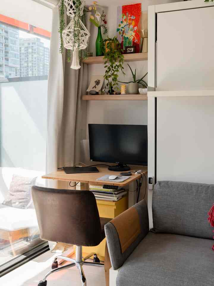 Natural-toned small home office with desk, office chair, wall shelves, and plants in a cozy atmosphere
