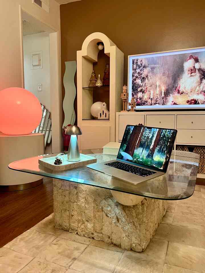 Warm brown and white toned living room featuring a glass coffee table with a laptop and simple ambient lighting creating a cozy atmosphere