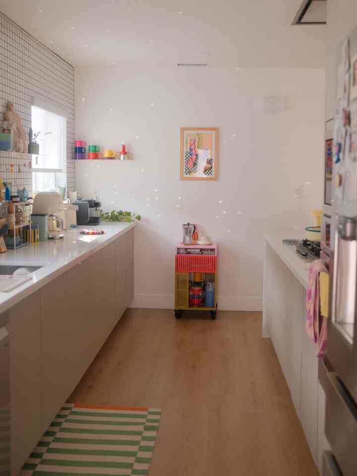 White and wood tone kitchen featuring colorful mugs and kitchenware creating a cozy home cafe atmosphere