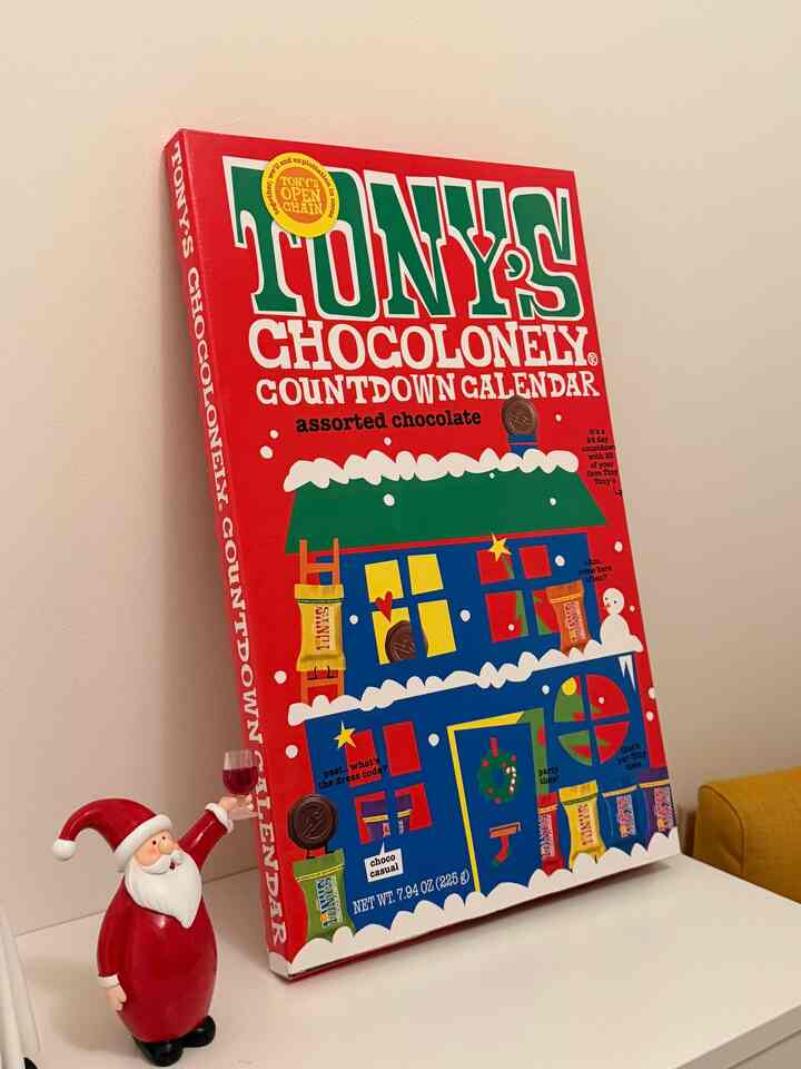 Simple living room with white walls and yellow shoe cabinet, featuring a red Tony's Chocolonely calendar and Santa figurine adding festive charm