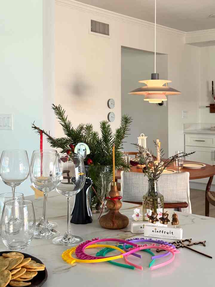 White and wood tone dining area featuring a table with candles and plants, showcasing a clean modern interior