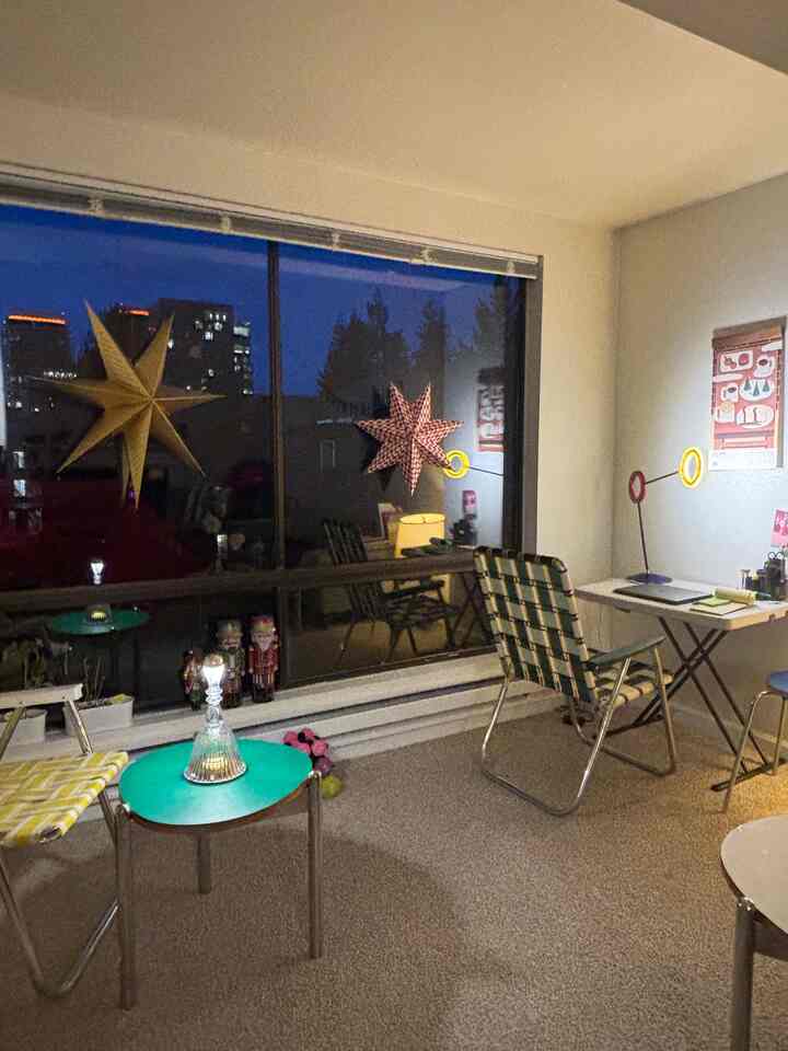 White-walled living room with beige rug, featuring green side tables and vintage-style chairs in a cozy home office setup