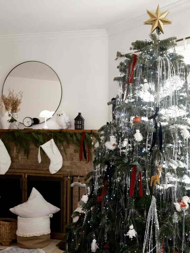 White and silver toned living room featuring a fireplace and a decorated Christmas tree with cozy holiday ambiance