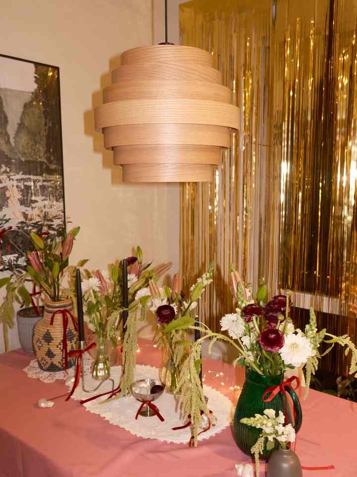 Warm brown and pink toned dining room featuring vases and a pendant light, creating a cozy home party atmosphere