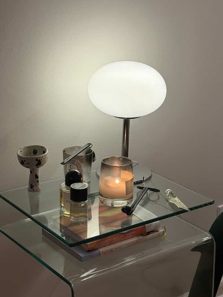 A quiet corner, softly lit ✨

An S-shaped glass side table, a scented candle with its snuffer, and a small table lamp glowing gently. Simple forms, warm light — the kind of setup that makes the room feel calm without trying too hard.

#OhouseGlow #cozycorners
#sidetable #softlighting #homeaesthetic
#minimalhome #quietmoments #winterathome
