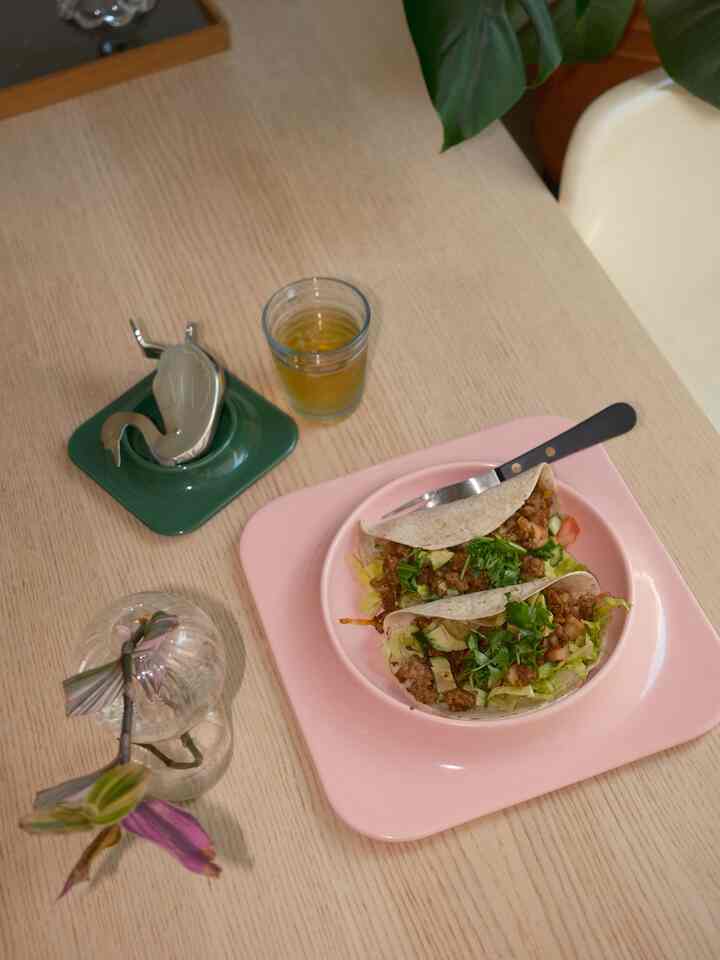 Natural tone dining room featuring pink plate with tacos and plant decoration, creating a cozy setting