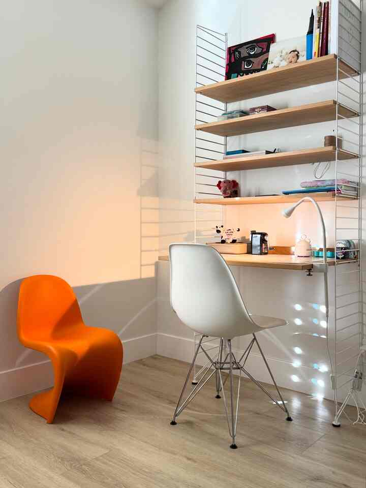 Natural color kids' room featuring wood flooring, wall shelves, white walls, and an orange children's chair