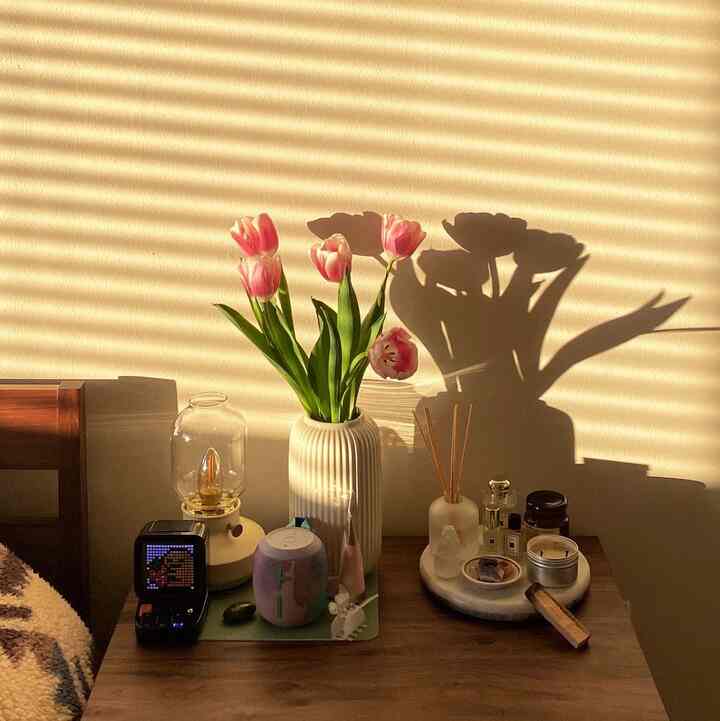 Warm brown wood nightstand in bedroom with white vase and pink tulips, creating a cozy atmosphere