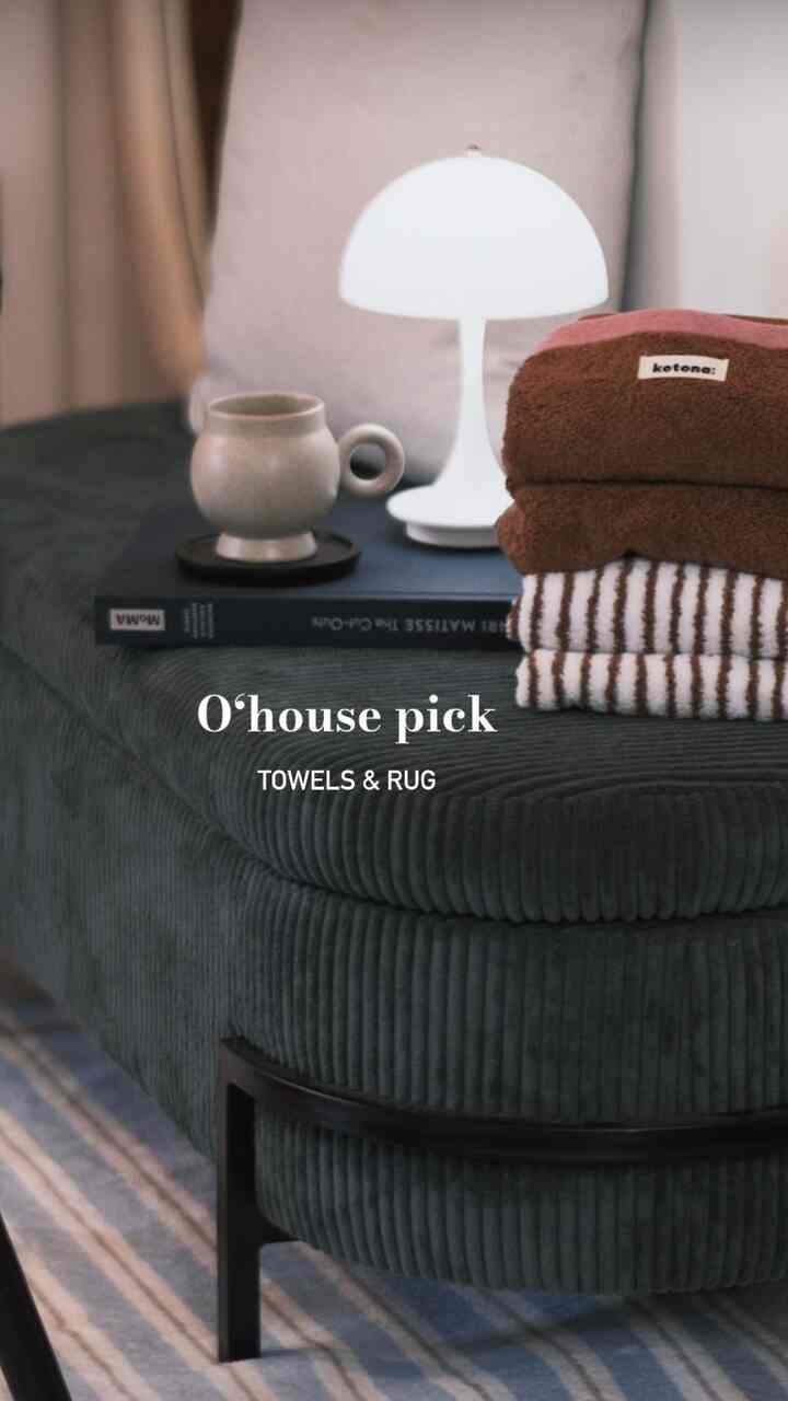 Natural-toned living room ottoman with soft brown towels and a blue striped rug