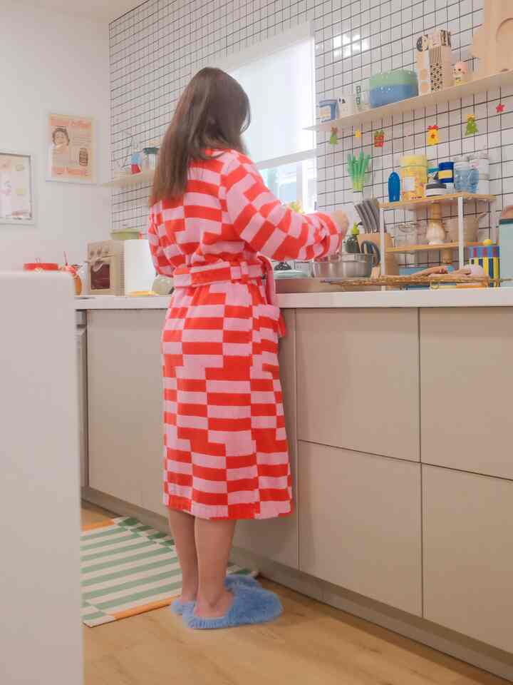 Beige kitchen space with a person in red checkered robe cooking, creating a cozy atmosphere