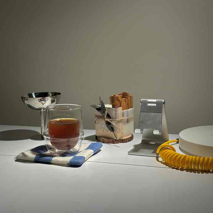 Cozy home cafe setup on a white table featuring coffee cup, candle, and silver metal decor