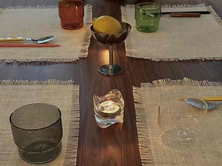 Warm wood tone dining room featuring a 4-person dining table with candles, glassware, and cutlery arranged for an inviting setting