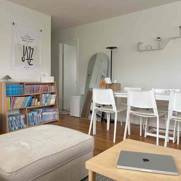 White and wood tone living room featuring sofa and bookshelf with a simple, warm atmosphere