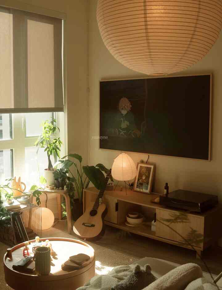 Natural modern living room with warm wood tones and natural light, featuring plants, a guitar, and a round wooden coffee table creating a cozy atmosphere