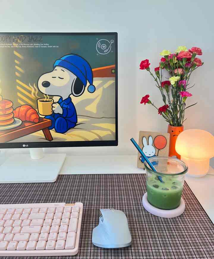 White-toned home office featuring a pink keyboard, colorful vase, and tartan table runner with a cozy remote work atmosphere