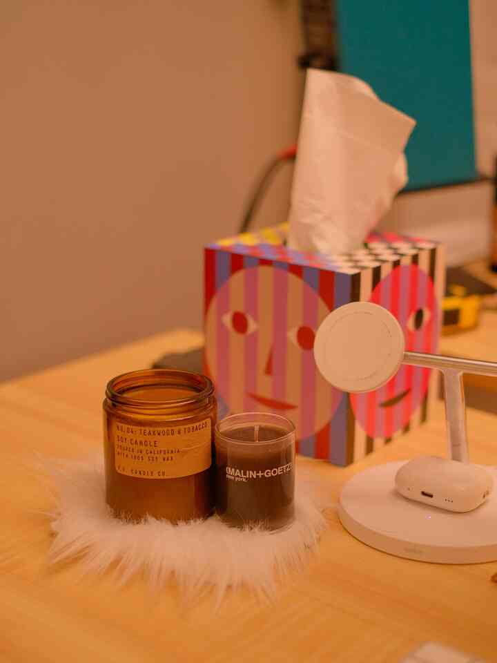 Warm wood tone home office desk featuring candles and neat accessories, creating a cozy atmosphere