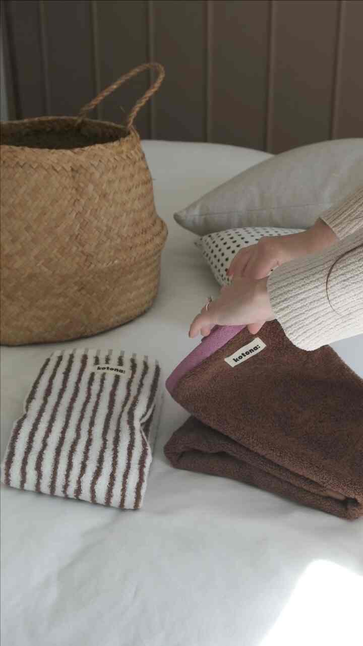 Natural tone bedroom featuring beige woven basket and brown towels on cream bedding