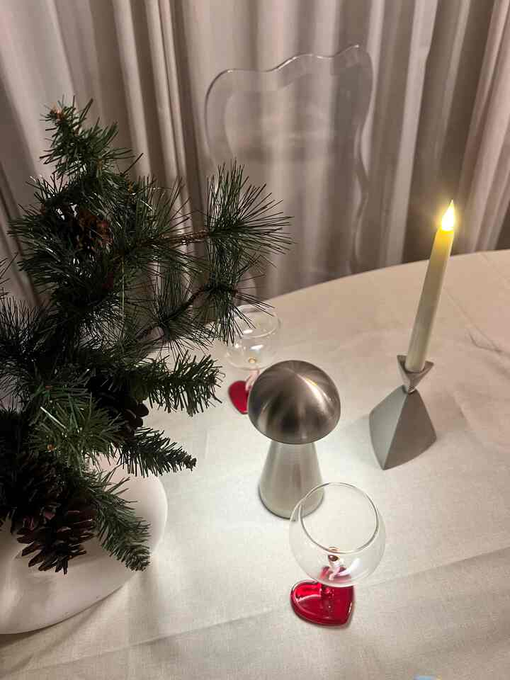 White and silver toned dining table with simple vase, candle, and wine glasses creating a cozy atmosphere