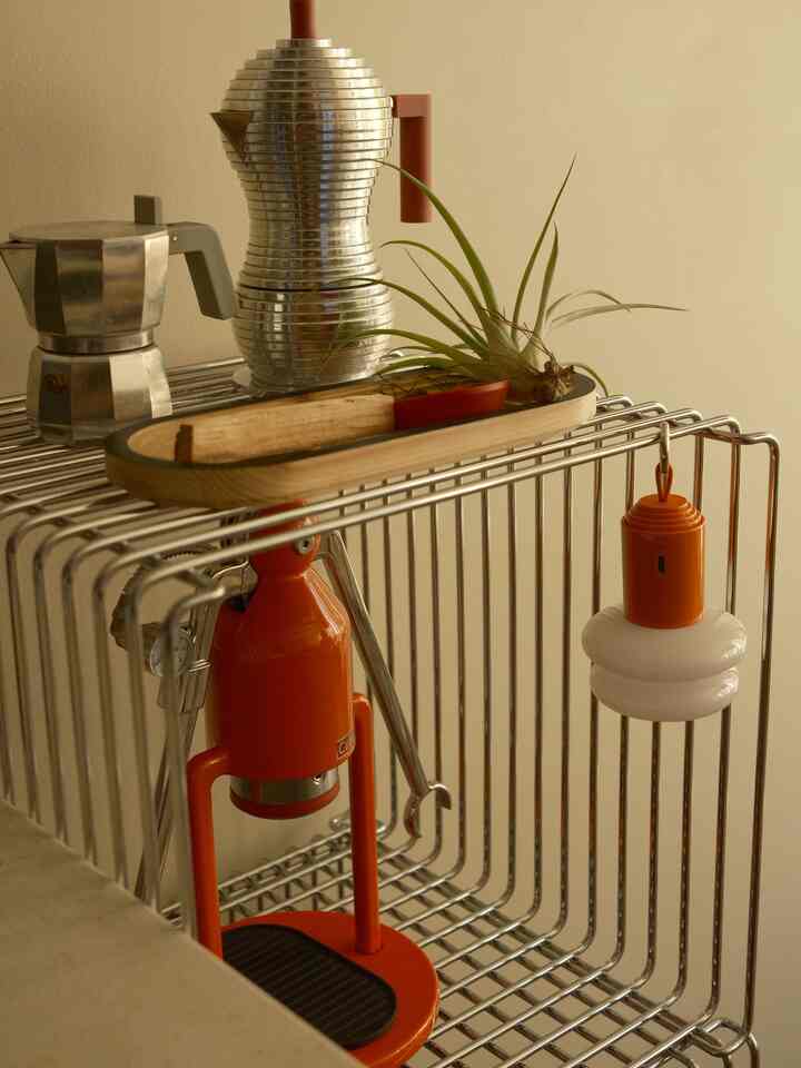 Warm beige wall kitchen home cafe featuring metal shelving and orange coffee equipment, with a cozy atmosphere