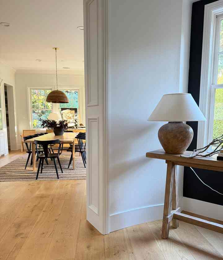 Wood tone and white dining room featuring a console table with table lamp in a modern entrance area