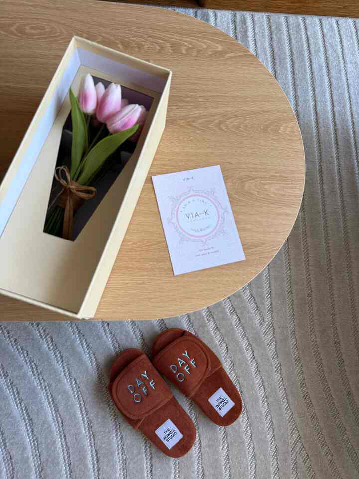 Natural brown-toned balcony space featuring wooden coffee table, pink tulips in box, and brown slippers creating a cozy atmosphere