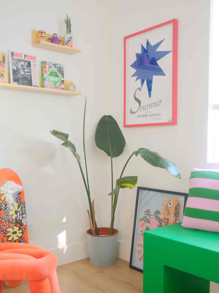 Bright white-walled home office corner with natural light, featuring green plant and vibrant furniture for a cozy atmosphere
