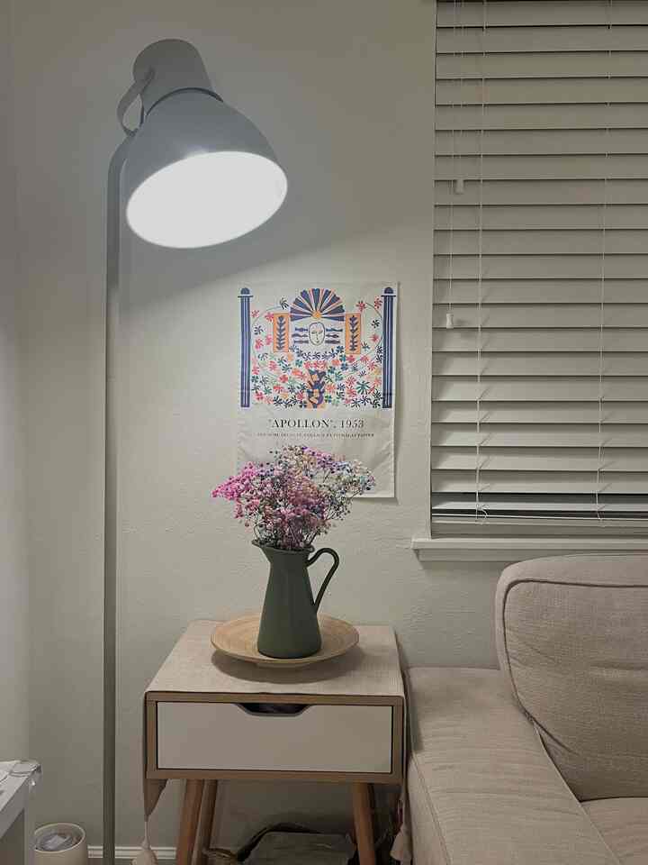 Simple natural living room with a light beige sofa and side table holding a green vase with colorful flowers