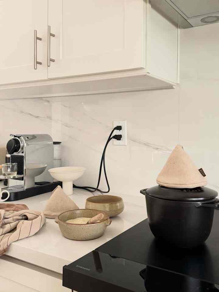 Modern kitchen with white and black tones featuring a coffee machine, pottery, and cast iron pot neatly arranged