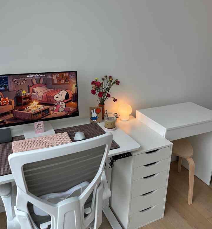 White and wood tone home office featuring a clean desk with computer setup and a vanity, creating a simple and organized space