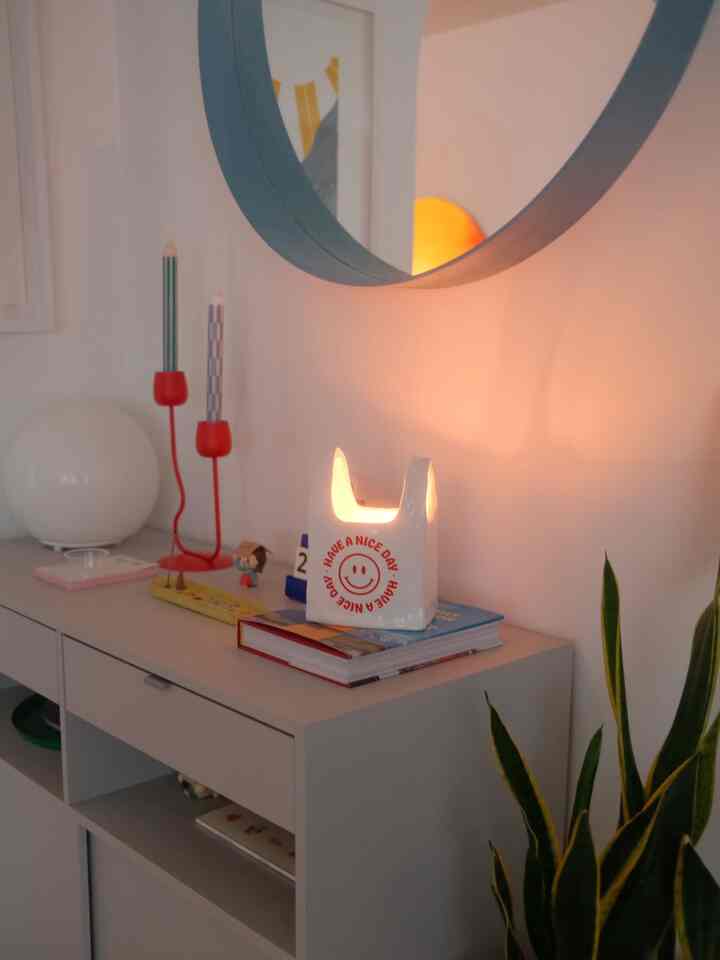 White-toned entrance corner featuring a round mirror, candles, and a table lamp creating a cozy atmosphere