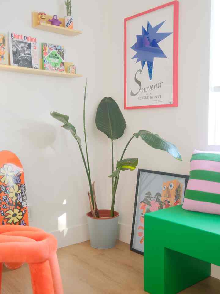 Bright home office corner with white walls, yellow shelves, green plant, and orange stool giving a natural, minimal vibe