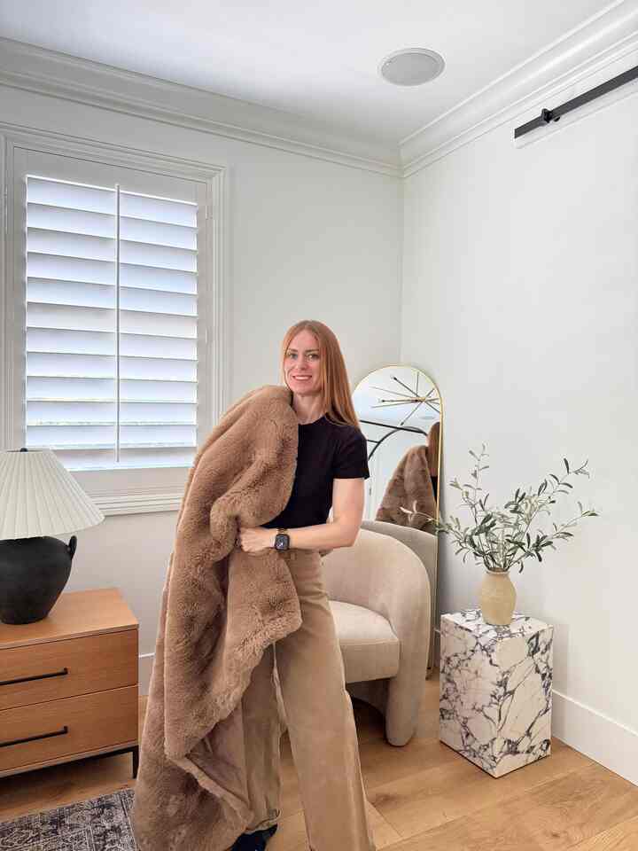 Natural beige and brown tone bedroom featuring beige armchair and marble side table with cozy atmosphere