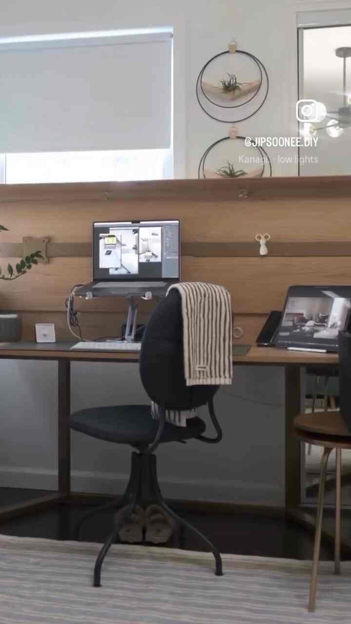 Natural tone home office featuring a wooden desk, black office chair, striped towel and rug creating a cozy atmosphere