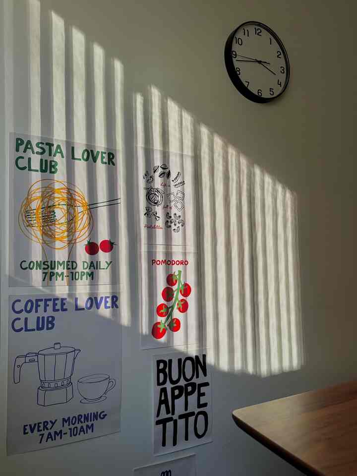 White wall adorned with colorful posters and a warm wood tone table edge visible in a kitchen space