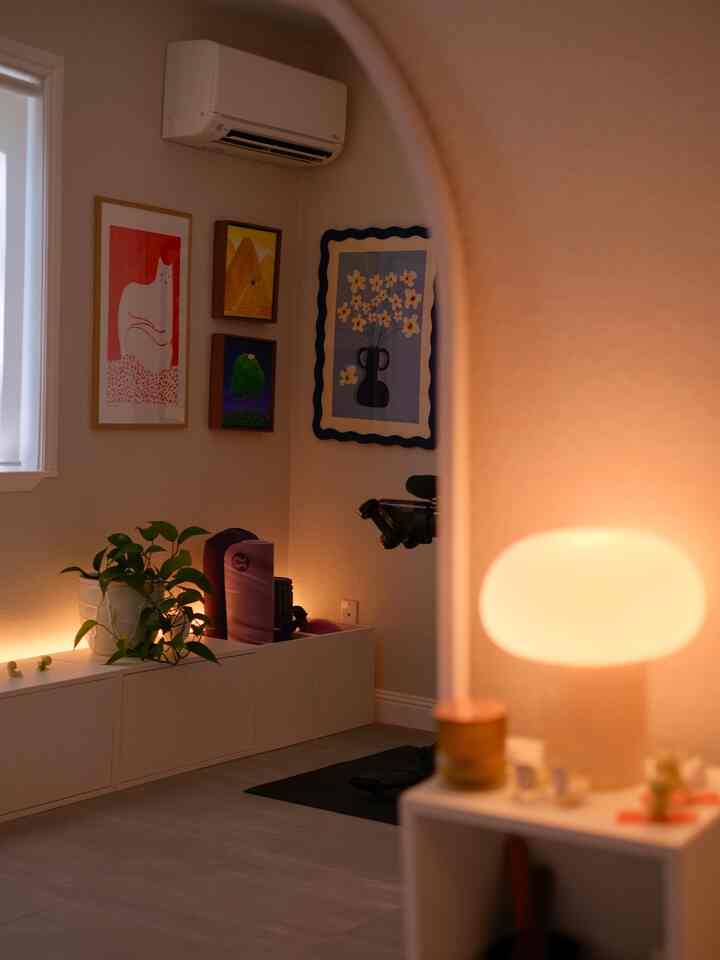 Natural modern interior with white walls and storage unit, featuring cat posters and warm ambient lighting in a cozy living room-like space