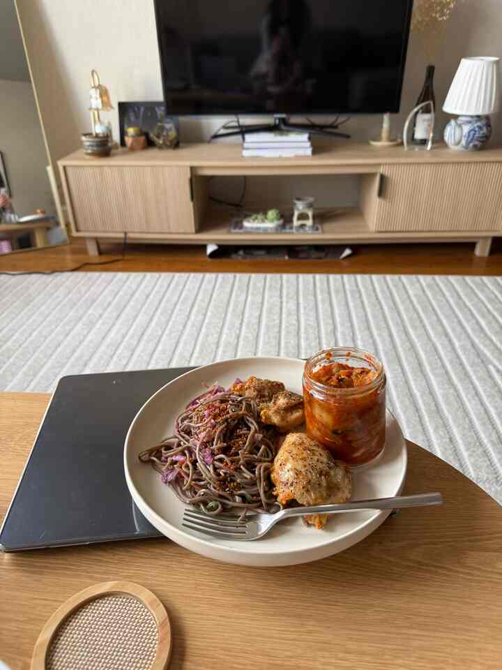 Wood tone and white living room featuring a coffee table with a plate of food and kimchi jar, creating a cozy and relaxed atmosphere