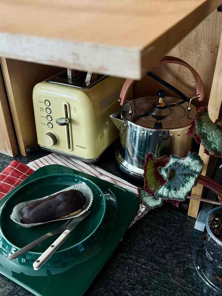 Cozy kitchen corner with warm beige wood and green plates, featuring a toaster and electric kettle