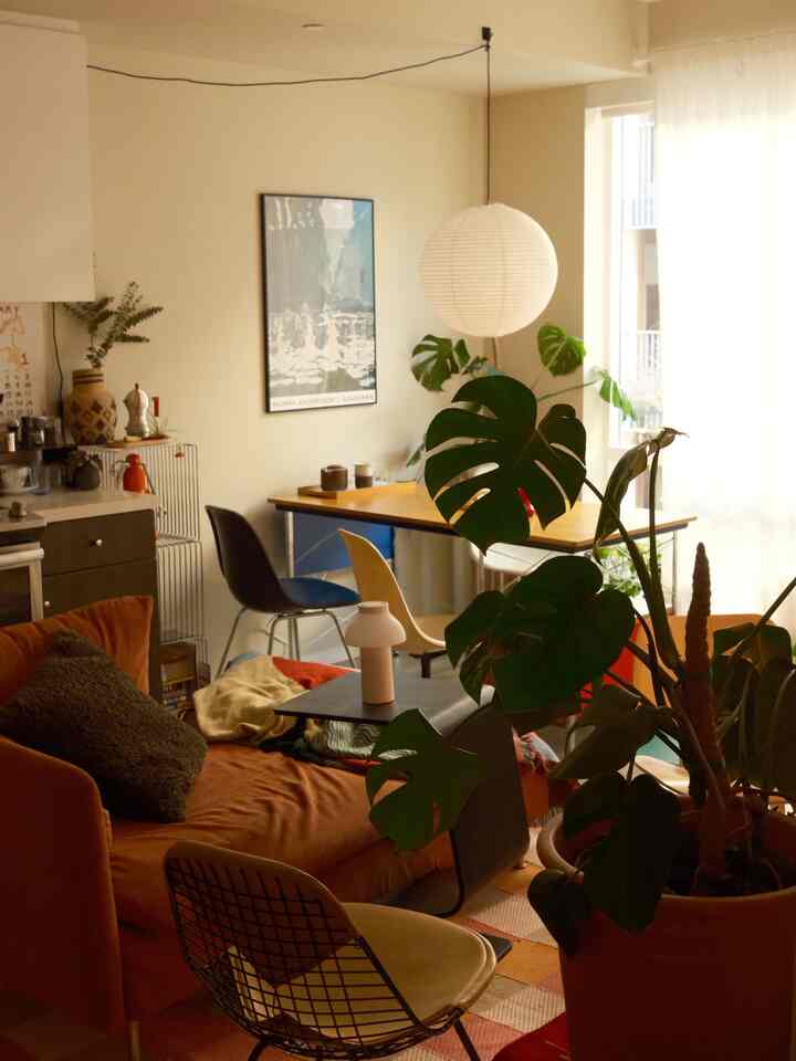 Natural-toned beige walls and wood-tone dining table with an orange sofa in a living room and kitchen space